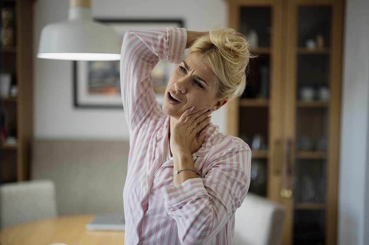 Persona che porta una mano al collo: fotografia illustrativa del dolore cervicale